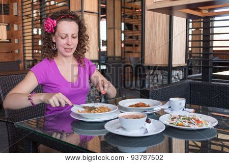 Woman eating pasta at a table in a restaurant