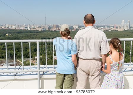 Grandfather with grandchildren admire the city view from the roof