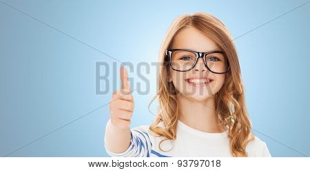 education, school, childhood, people and vision concept - smiling cute little girl with black eyeglasses showing thumbs up gesture over blue background