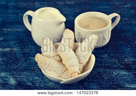 Homemade cookies twisted sprinkled with powdered sugar on a dark background. Selective focus.