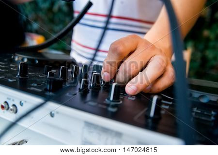 Close-up image of mixing console and DJ's hands during his job at party
