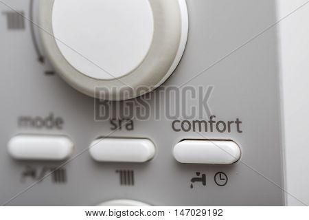 Close up on comfort button in control panel of central heating and DHW.