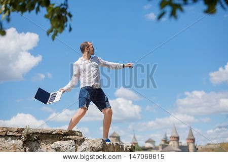 young man throws a laptop against blue sky