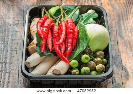 Tom yam ingredients set for Thai cooking in black plactic pallet on wooden table