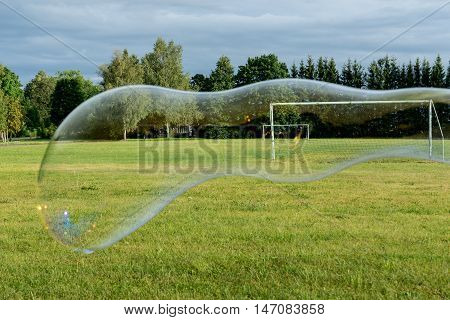 Big soap bubble green grass trees football ground and natural environment. Torma small village in Estonia. Europe