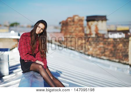 Young pretty girl sitting on a iron roof, close-up.