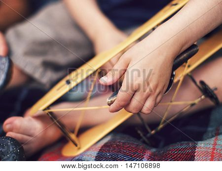 Child's hand holding toy yellow plane closeup