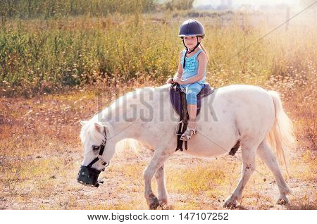 Little girl on the horse. White poni.