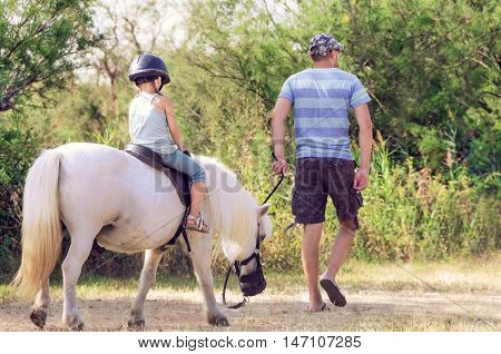 Dad teaches his daughter to ride a horse. Lesson with Riding Instructor.