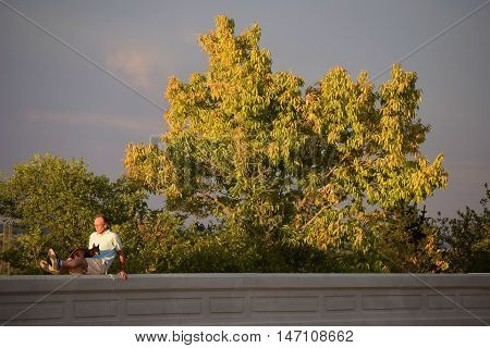 Denver, CO - September 12, 2016:  Person resting with his dog at Inspiration Point which is a place in Inspiration Park where people can enjoy views of Denver and the Rocky Mountains taken in Denver, CO.