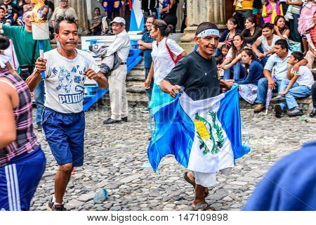 Antigua Guatemala - September 14 2015: Locals run by city hall with Guatemalan flag & lit torches during Guatemalan Independence Day celebrations
