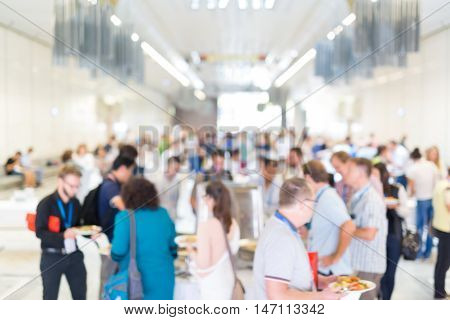 Abstract blurred people socializing during buffet lunch break at business meeting or conference.