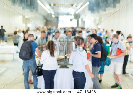 Abstract blurred people socializing during buffet lunch break at business meeting or conference.