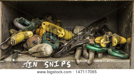 Selection of old plumbers tools with different coloured handles on a shelf.