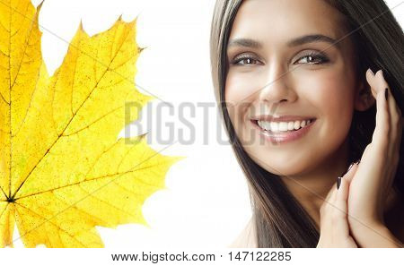 closeup portrait of attractive  caucasian smiling woman brunette isolated on white studio shot lips toothy smile face hair  looking at camera tooth hand holding yellow marple autumn leaves