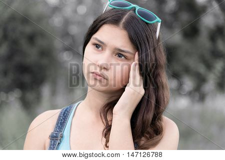 Portrait of a teen girl thinking about a problem on the nature