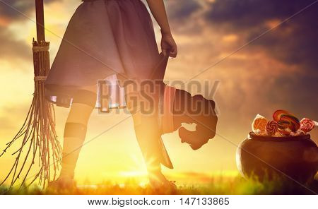 Happy Halloween! Cute little witch with a broomstick. Child girl in witch costume outdoors. 