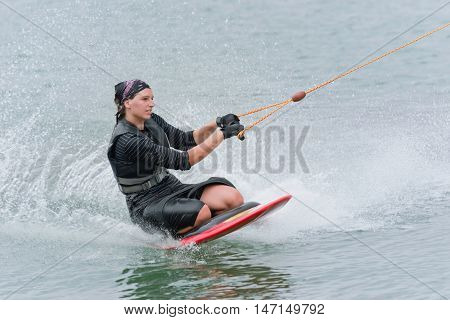 Young woman kneeboarding on lake, toned image, horizontal