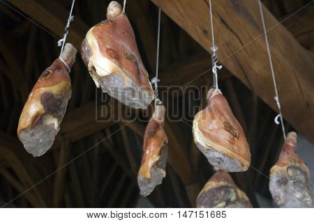 hams hang from very old wooden beams in Ghent Meat Hall