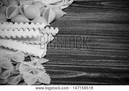 Pasta mix on dark wooden table background. Black and white