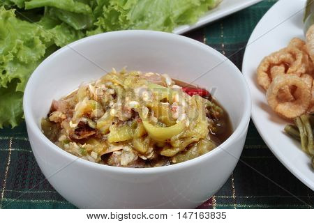 Close up a bowl of green chili dip " Nam Prik Num" served side dish. Selective focus.