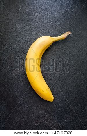 Yellow banana in the middle of gray slate