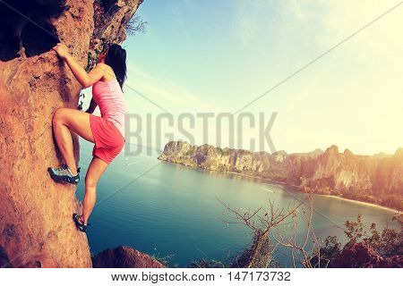 young woman rock climber climbing at seaside mountain rock
