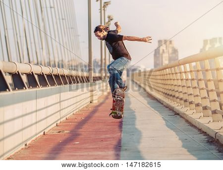 Skateboarder Skates And Doing Jumps Over A City Bridge. Free Ride Street Skateboarding