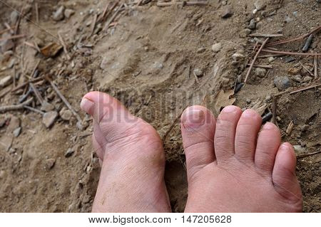 Small child's dirty feet on barren dry arrid ground