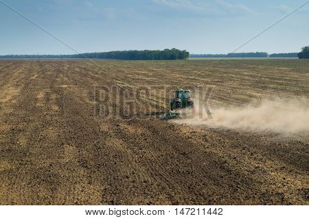 KRASNODAR REGION, RUSSIA - AUG 19, 2015: Modern green tractor plows field after harvesting, In 2015 in Krasnodar region yields reached record level - 58.4 centners per hectar