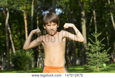 portrait of a boy in nature which shows his muscles