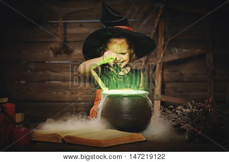 Halloween. child girl witch preparing a potion in the cauldron
