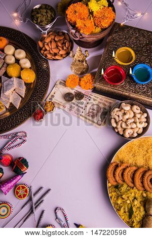 oil lamp or diya with crackers, sweet or mithai, dry fruits, indian currency notes, marigold flower and statue of Goddess Laxmi on diwali night while laxmi pujan or pooja