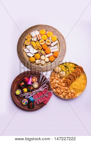 indian sweet food served with assorted fire crackers in separate plate showing diwali concept