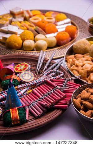 indian sweet food served with assorted fire crackers in separate plate showing diwali concept