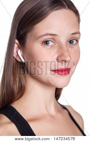 Young beautiful woman with freckles and wireless earphones on her ears. studio shot.