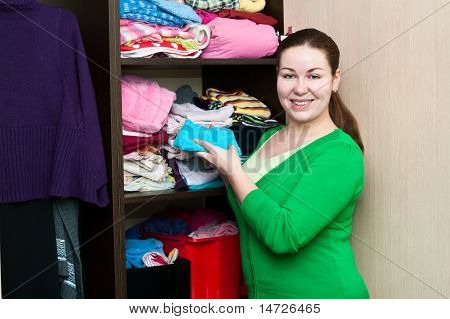 สาวคอเคซัสในตู้เสื้อผ้าชุดสิ่งบนมี Shelfs