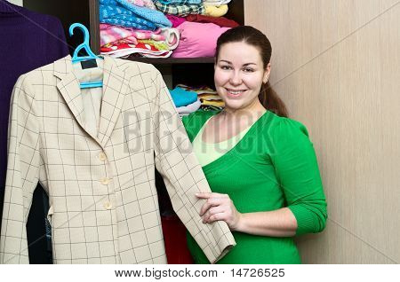 เก็บกระเป๋าเดินทางแบบสาวคอเคซัส และยืนอยู่ใกล้ตู้เสื้อผ้า สิ่งที่บรรจุในชั้นการ