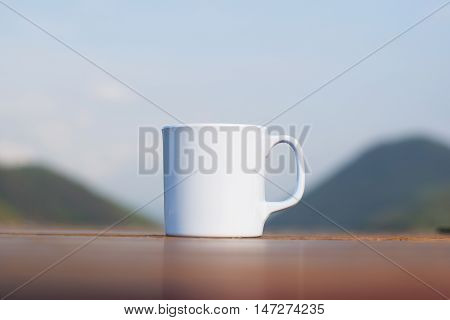 Coffee cup on wooden table and mountain (vintage background)