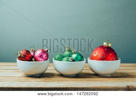 Christmas decorations and ornamnets on wooden table. Three bowls with christmas balls. Retro filter effect