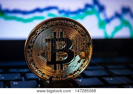 A golden bitcoin with keyboard and graph background. trading concept of crypto currency