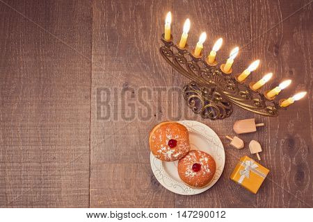 Menorah and sufganiyot on wooden table for Hanukkah celebration. View from above
