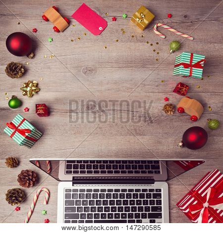 Laptop computer with Christmas decorations on wooden background. Christmas mock up template. View from above