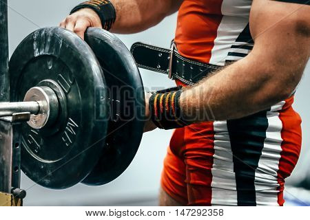 male athlete powerlifter preparing barbell for bench press in sport gym