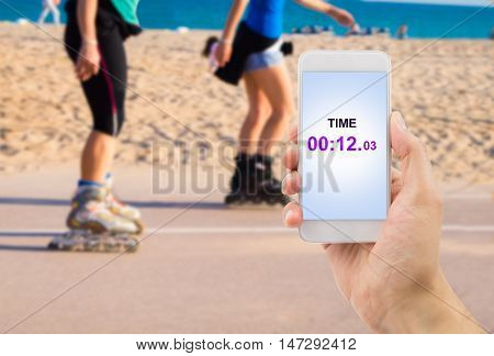 hand holding the smartphone with the chronometer function to measuring the time of the skaters race
