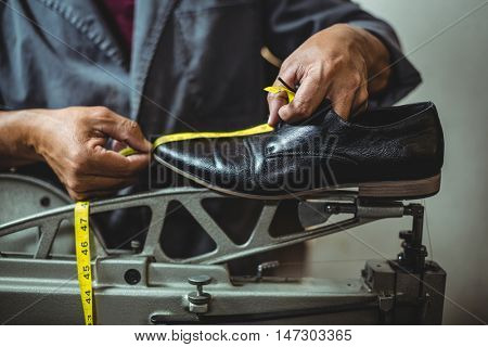 Shoemaker measuring a shoe with measure tape in workshop