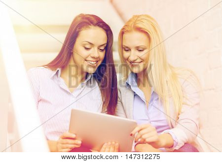 business, technology and startup concept - smiling creative team with tablet pc computer sitting on staircase