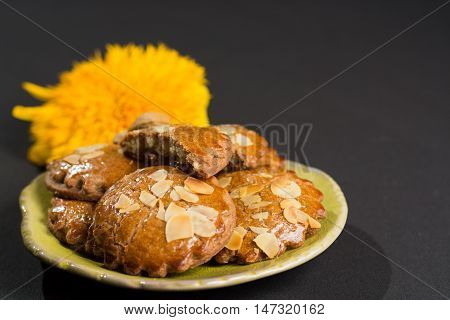Typical Dutch filled spicy cookies with almonds on autumn colored and dark background