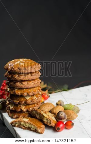 Typical Dutch filled spicy cookies with almonds on autumn colored and dark background