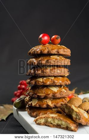 Typical Dutch filled spicy cookies with almonds on autumn colored and dark background